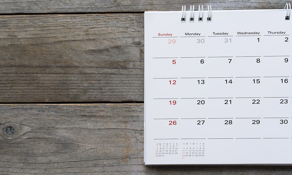 2022 Holiday Schedule - Calendar With Binder Rings Resting on a Wooden Table